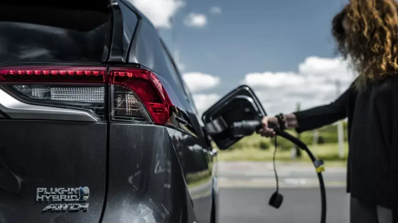 Kobieta podłącza ładowarkę do hybrydowego SUV-a. Zastanawiasz się, ile kosztuje ładowanie elektryka?
