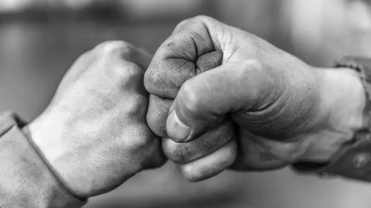 Zwei Fäuste stoßen zusammen, ein Zeichen von Solidarität und Verbundenheit.