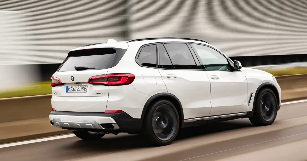 Białe BMW X5 M50d pędzi po autostradzie, zostawiając za sobą rozmyte tło.