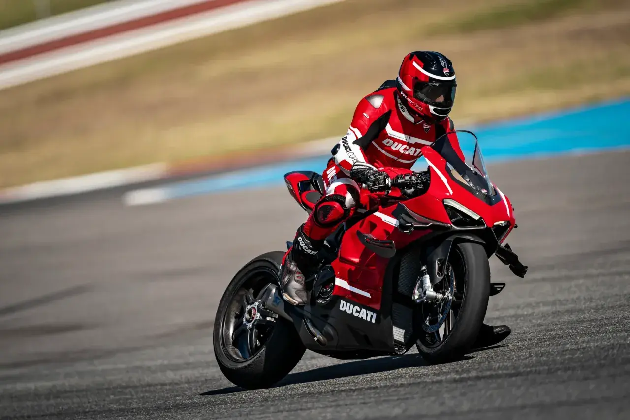 Motocyklista w czerwonym kombinezonie śmiga na torze wyścigowym na swoim czerwonym Ducati Panigale V4.