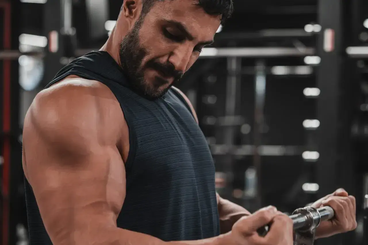 Mężczyzna ćwiczy biceps na siłowni. Zastanawia się nad cytrulina skutki uboczne, ale skupia się na treningu.