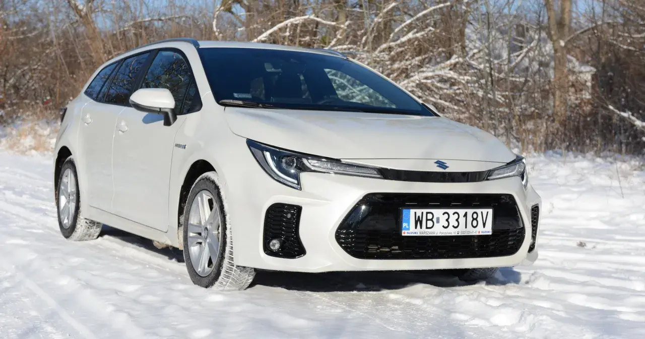 Biały Suzuki Swace Hybrid na śniegu, gotowy na zimowe wyzwania.