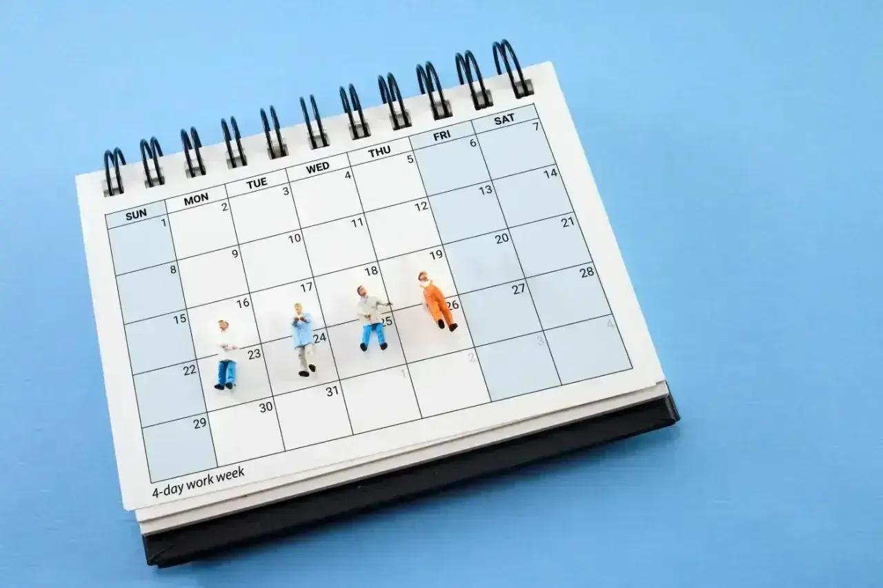 Miniaturki ludzi na kalendarzu z napisem "4-day work week". To karta nauczyciela zmian, która pokazuje, jak można zaplanować krótszy tydzień pracy.