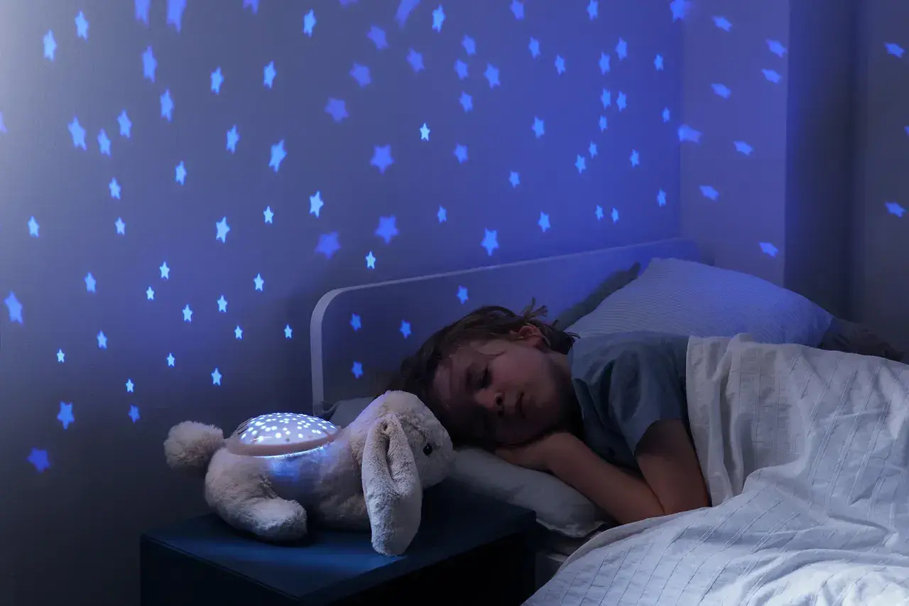 Uroczy króliczek z projektorem dla niemowlaka rzuca na ścianę niebieskie gwiazdki, tworząc magiczną atmosferę do snu.