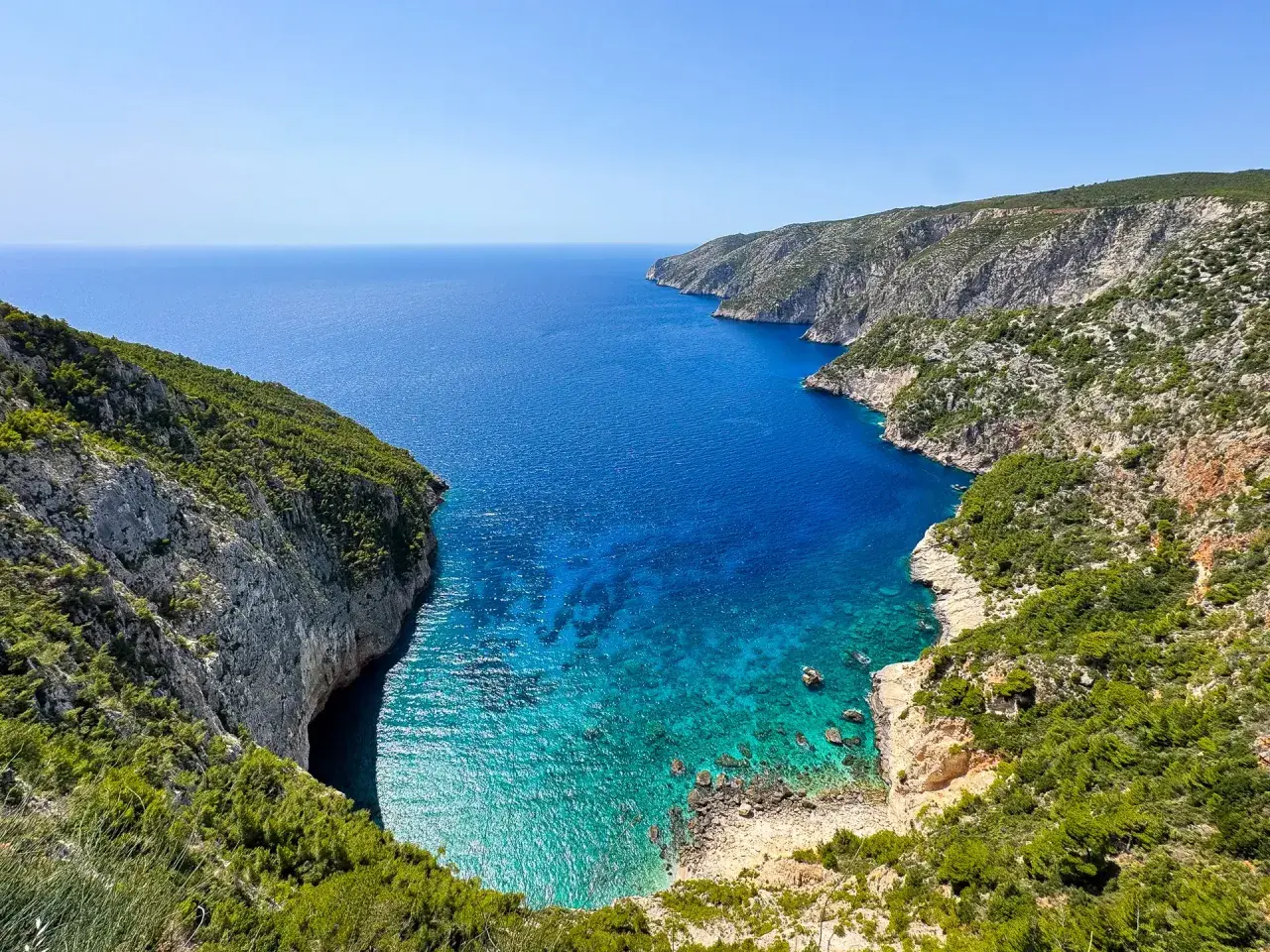 Widok na zatokę z klifami porośniętymi zielenią. Idealne miejsce na zakynthos wycieczki fakultatywne, by podziwiać turkusową wodę.