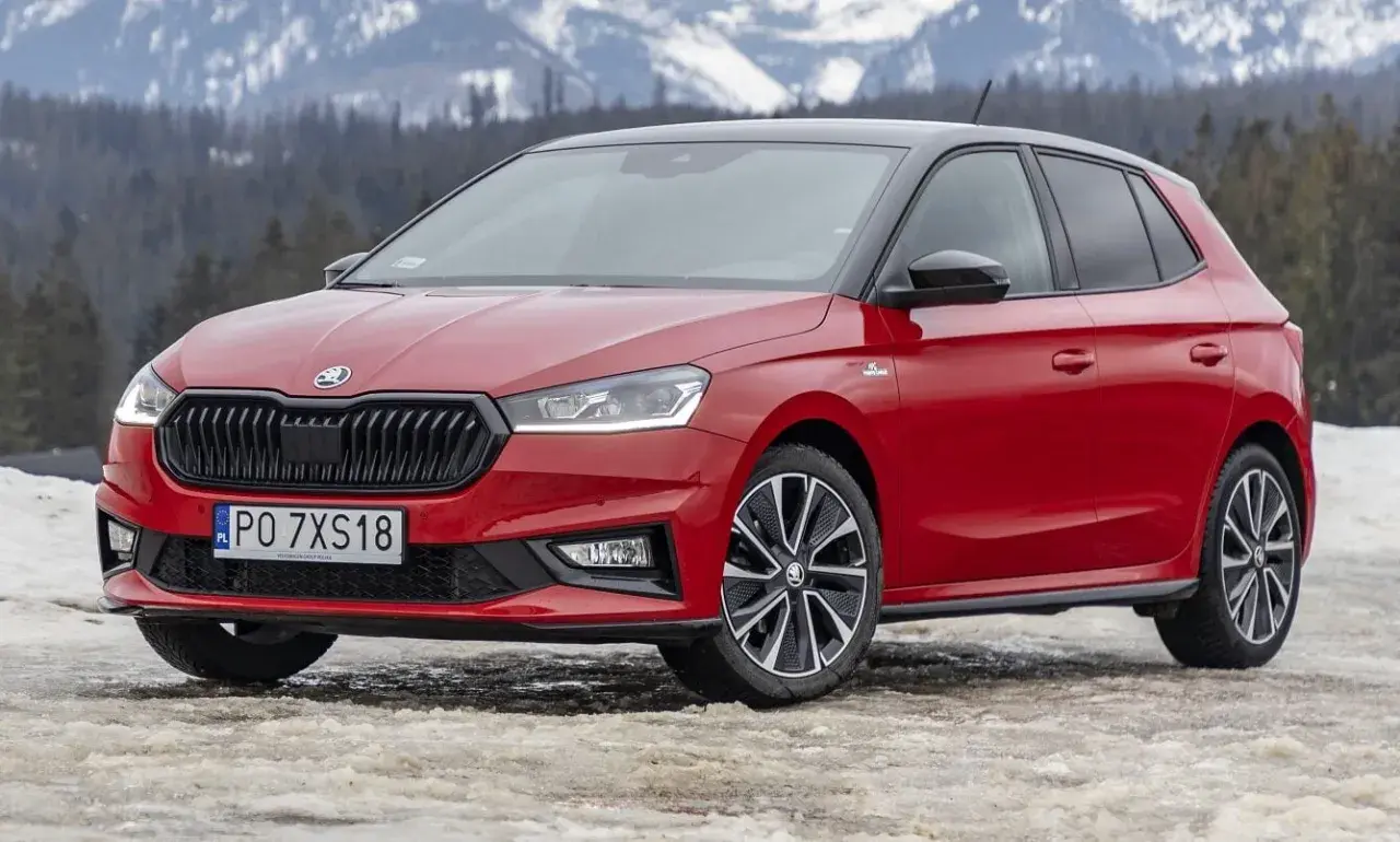 Czerwona Skoda Fabia Monte Carlo z czarnym dachem na tle ośnieżonych gór.