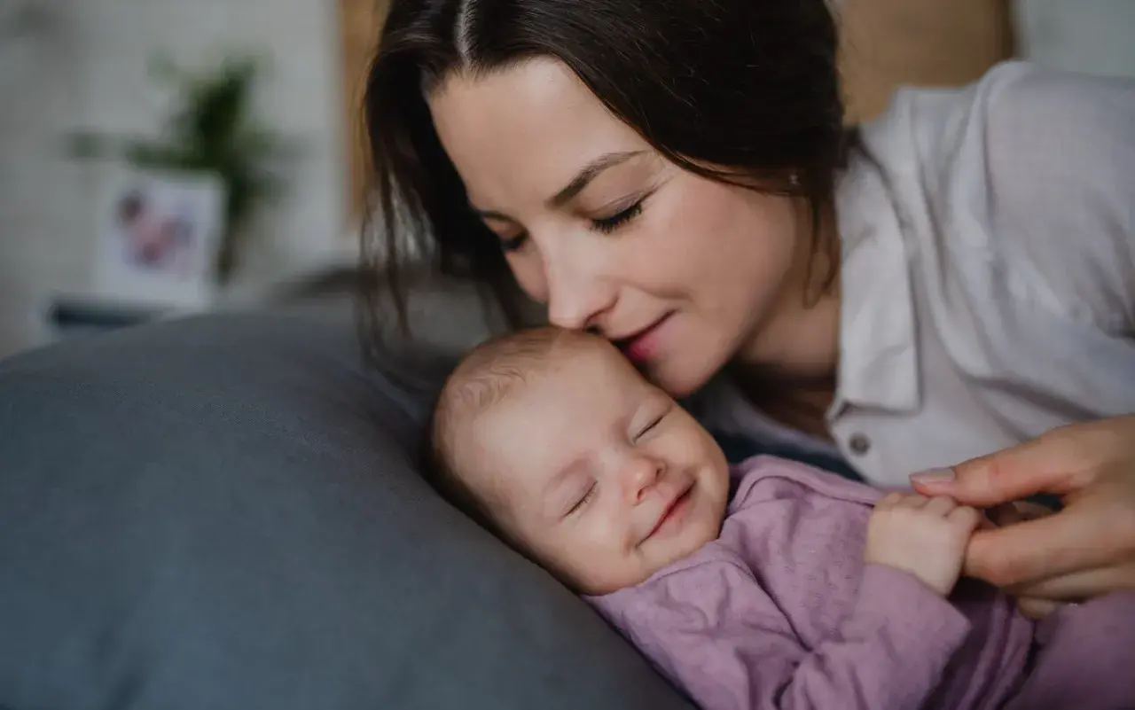 Mama całuje śpiące dziecko. Wkrótce wybierzemy dla niej słodkie imiona dla dziewczynki.