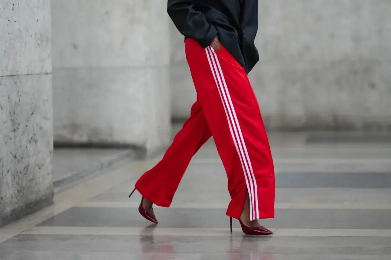 Czerwone spodnie dresowe z białymi lampasami i eleganckie szpilki. Odważne połączenie, które odpowiada na pytanie: jakie buty do dresów?