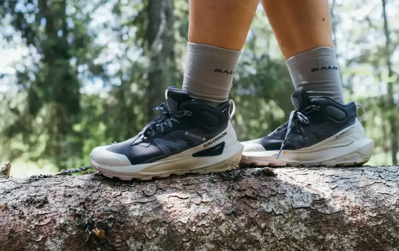 Buty trekkingowe Salomon na pniu drzewa w lesie. Salomon to firma znana z wysokiej jakości obuwia outdoorowego.
