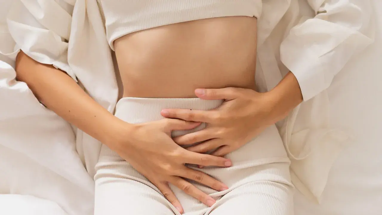 Kobieta trzyma się za brzuch, odczuwając ból. Może to być jeden z objawów endometriozy jelitowej.