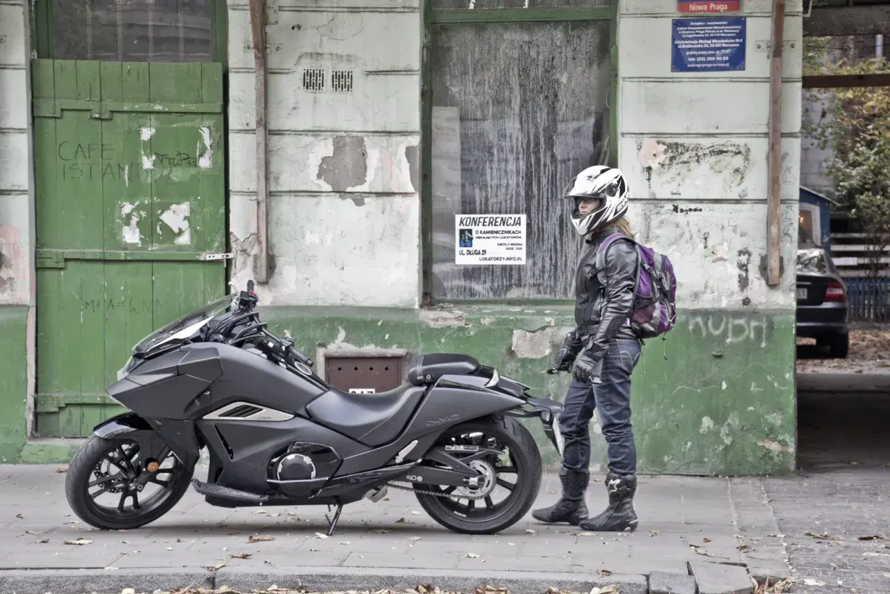 Motocyklista w kasku obok swojego futurystycznego Honda NM4 Vultus.
