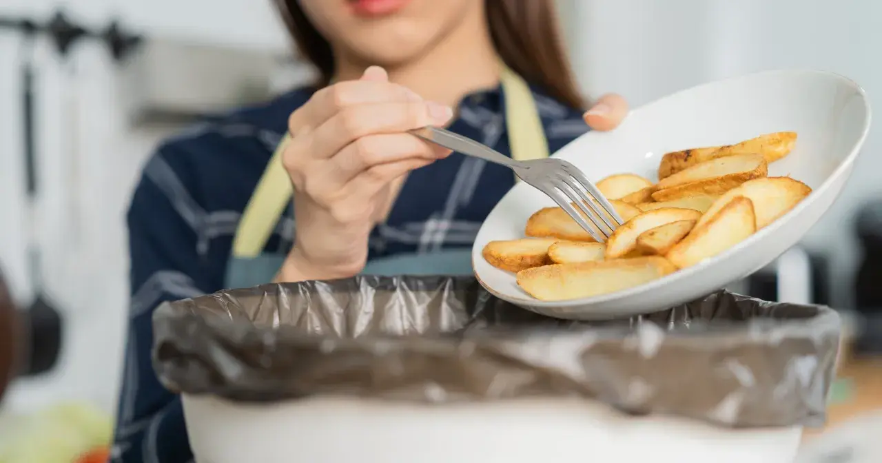 Kobieta wyrzuca frytki, zaczynając drogę do tego, jak obniżyć cholesterol bez leków. Zdrowa dieta to klucz.