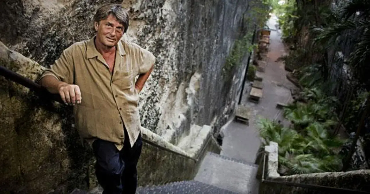 Mike Oldfield, znany muzyk, stoi na kamiennych schodach. Może to miejsce, gdzie mieszkał z żoną.