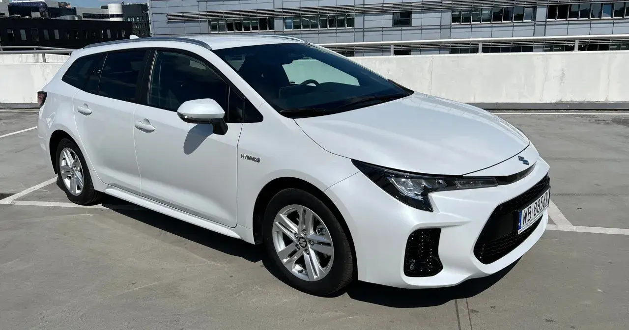 Biały Suzuki Swace Hybrid na parkingu. Elegancki kombi z nowoczesnym designem, gotowy na każdą podróż.