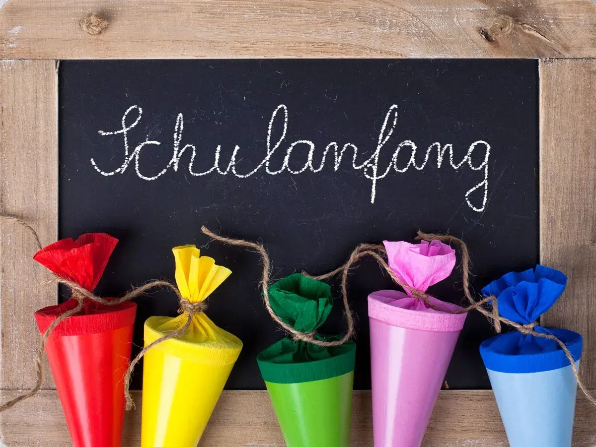 Bunte Schultüten vor einer Tafel mit "Schulanfang" für die Einschulung Hessen 2025.