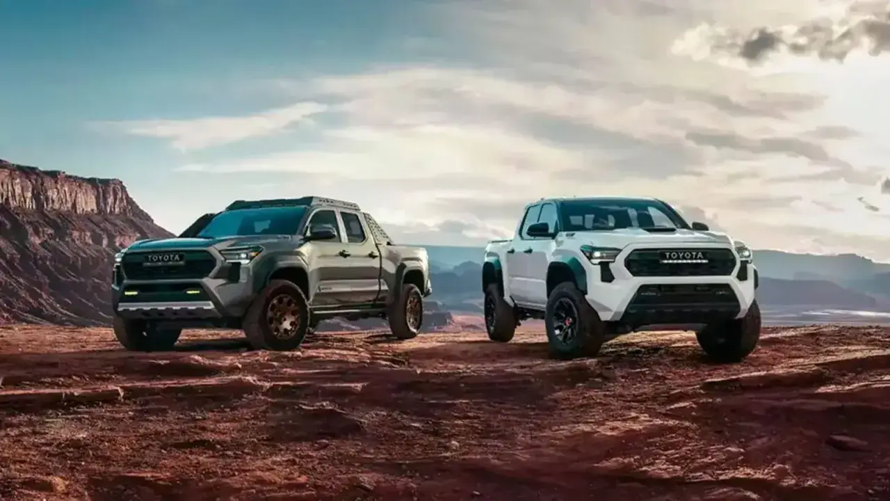 Dwa nowe modele toyota pickup, biały i szary, gotowe na przygodę w surowym, pustynnym krajobrazie.