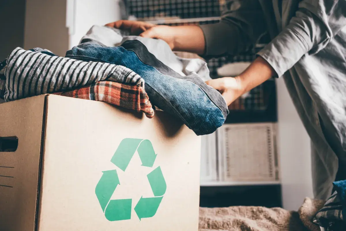 Pudełko z ubraniami i symbolem recyklingu. Wiesz, gdzie można oddać ubrania za darmo?