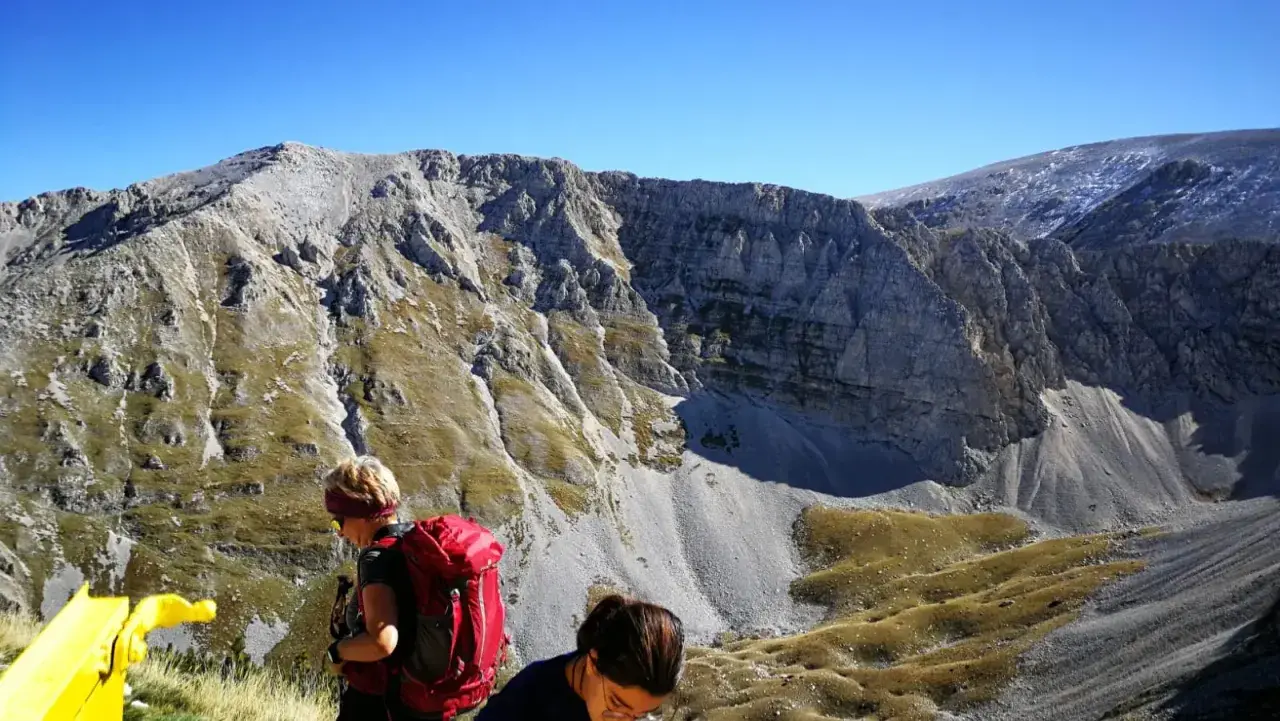 Escursionisti con zaini rossi ammirano il panorama montuoso vicino al bivacco Fusco.
