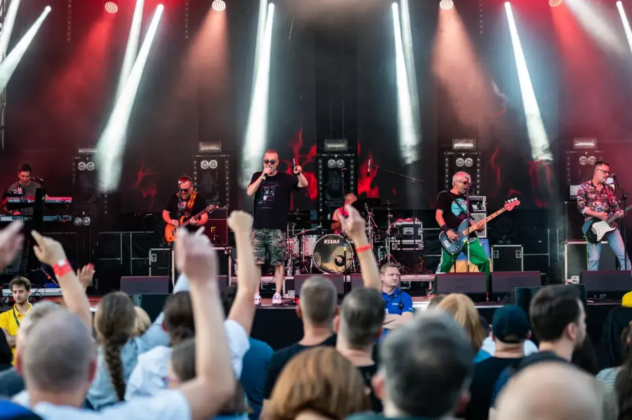 Zespół gra na scenie podczas festiwalu w Jarocinie. Widać publiczność, światła i instrumenty.