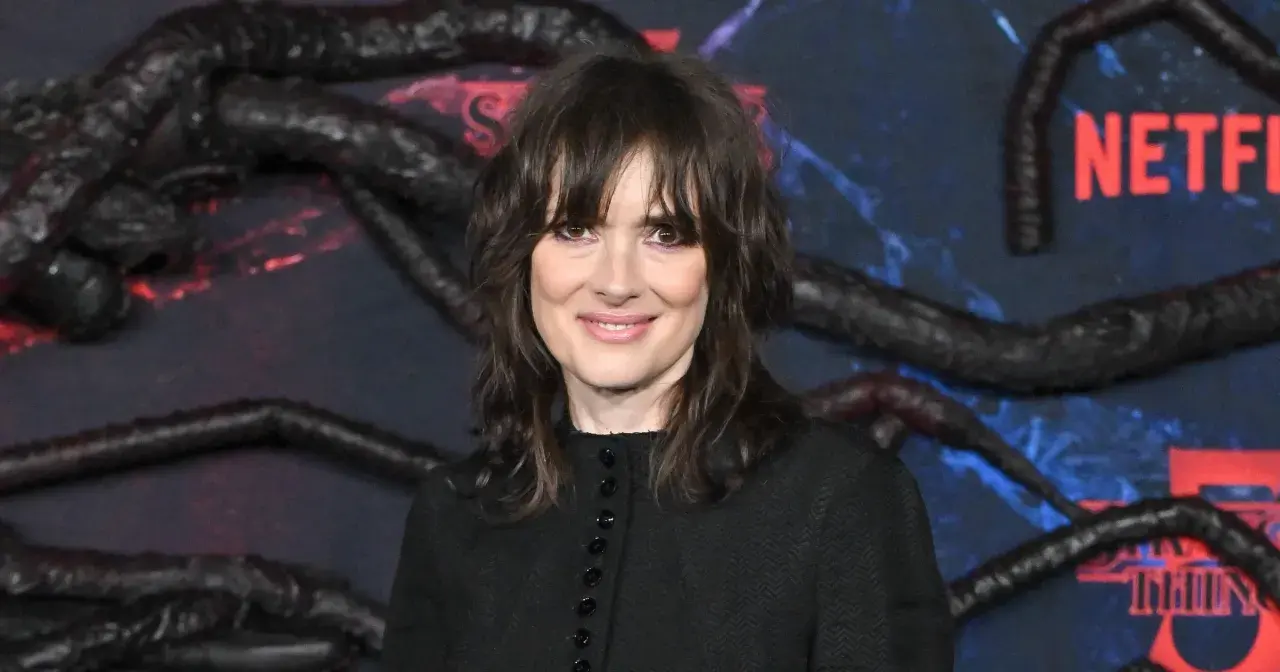 Winona Ryder, gwiazda filmów i seriali, w tym "Stranger Things", na tle dekoracji z mackami i logo Netflix.
