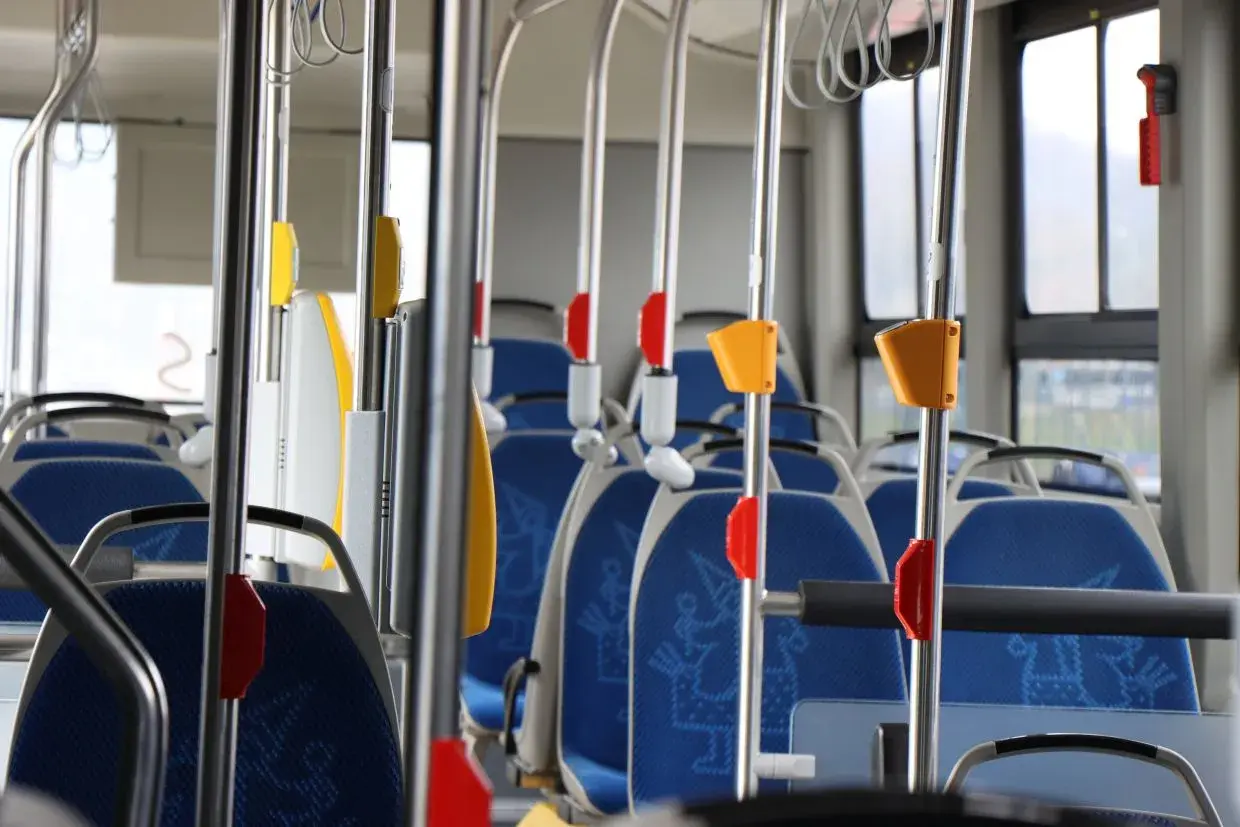 Wnętrze autobusu 139 z niebieskimi siedzeniami i metalowymi poręczami.