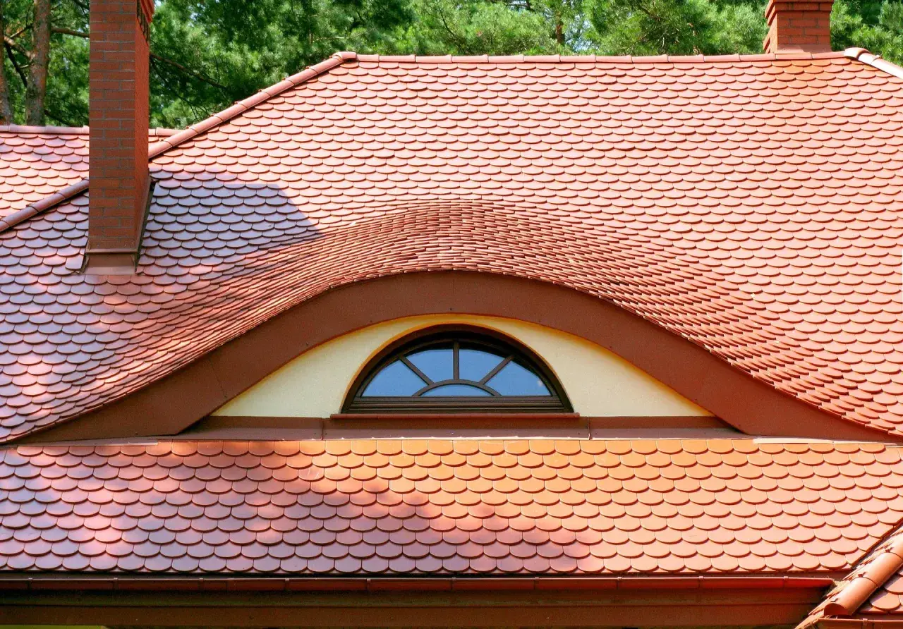 Ceglana dachówka ceramiczna w kształcie rybiej łuski, z ozdobnym lukarną. Idealna, by stworzyć stylowy dach.