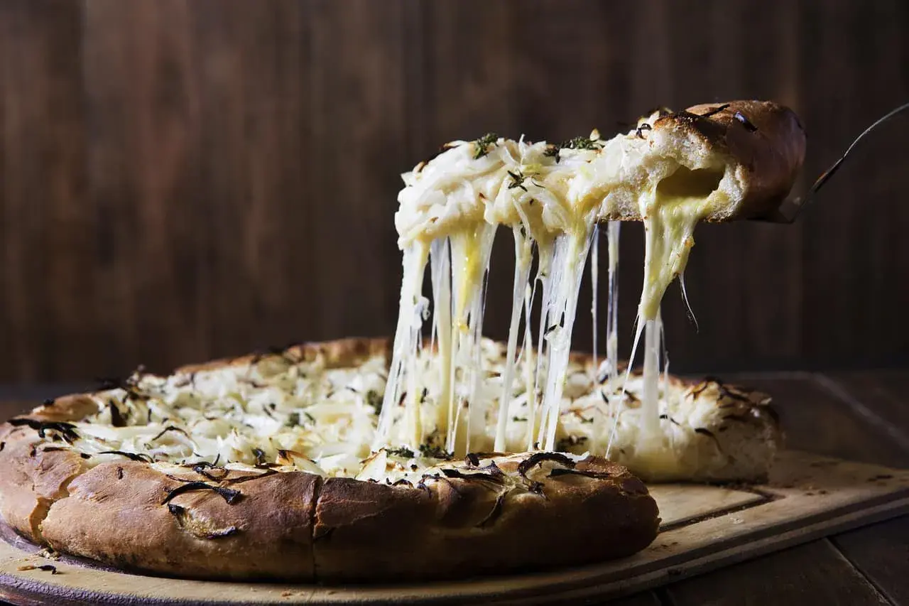 Rozpływający się ser z pizzy quattro formaggi ciągnie się w długich nitkach. Pyszny, gorący przysmak.