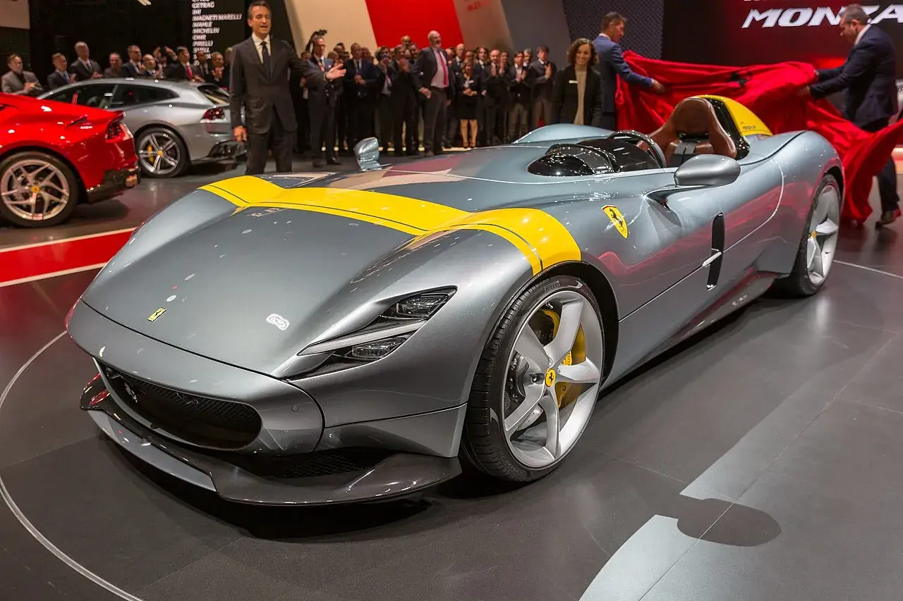 Szary Ferrari Monza SP1 z żółtymi pasami, odsłaniany na scenie.