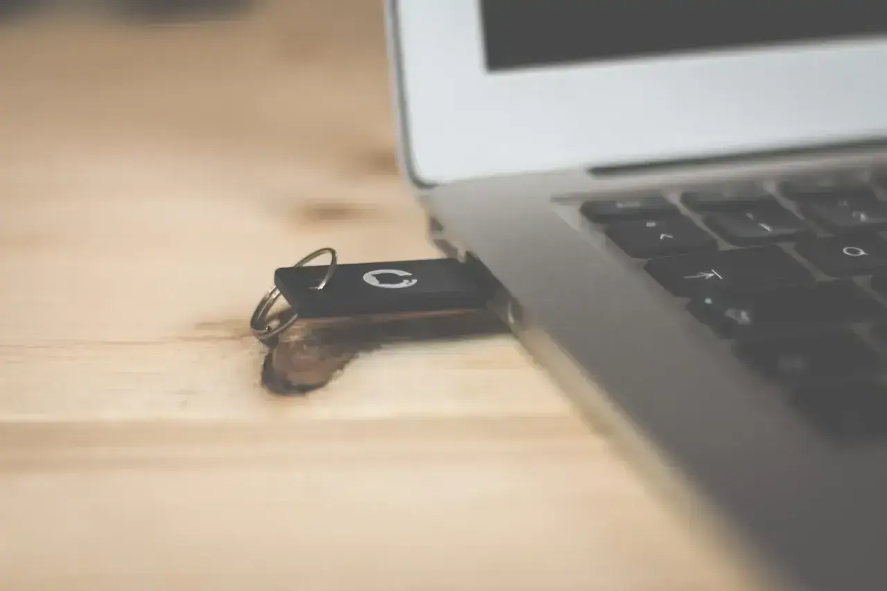 Pendrive z systemem Windows 10 bootable usb podłączony do laptopa na drewnianym biurku.
