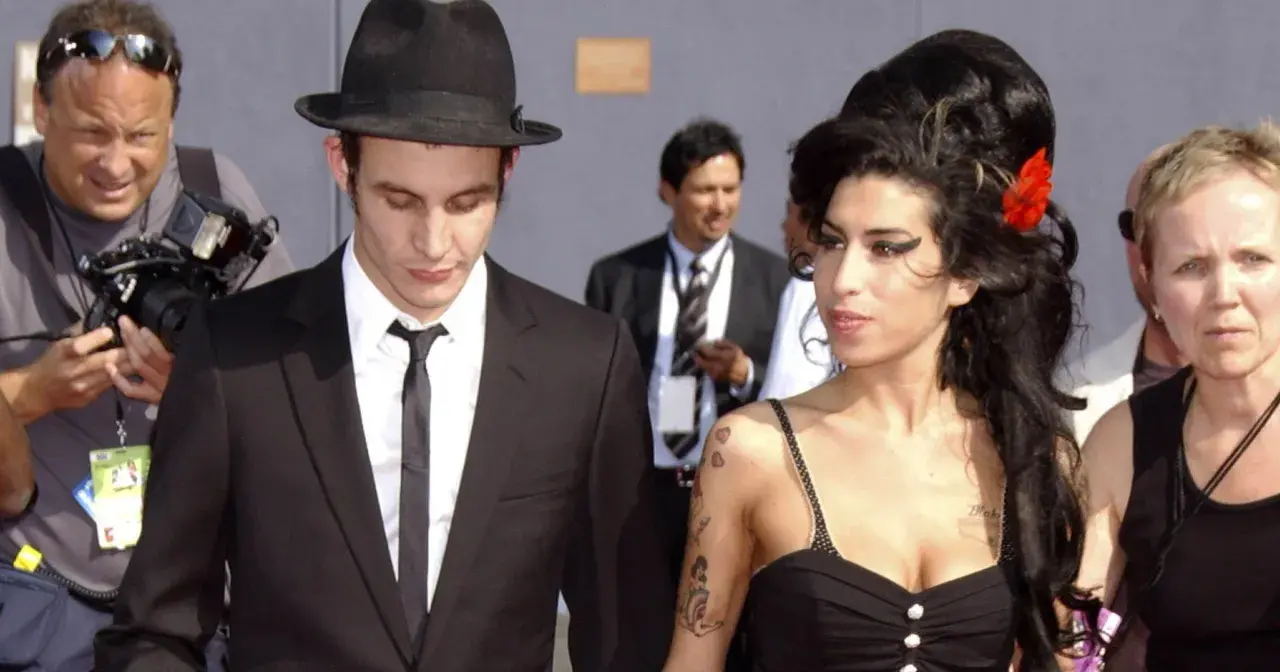Blake Fielder-Civil w czarnym garniturze i kapeluszu obok Amy Winehouse z czerwoną różą we włosach.
