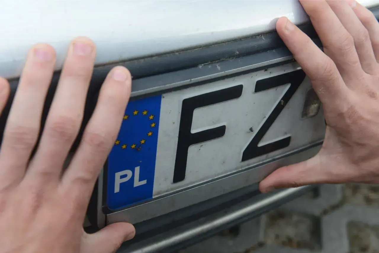 Dwie dłonie trzymają polską tablicę rejestracyjną z literami FZ.