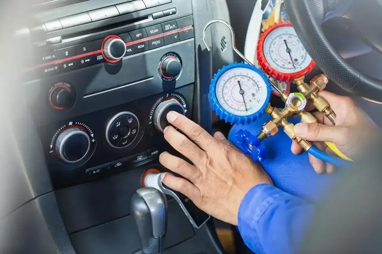 Mechanik sprawdza ile czynnika do klimatyzacji pozostało w samochodzie, używając manometrów.