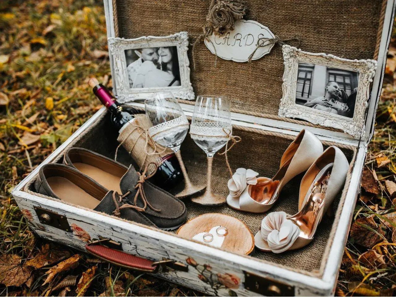 Elegancki prezent na ślub cywilny bez wesela: buty, wino, kieliszki, obrączki i zdjęcia pary w ozdobnej skrzyni.