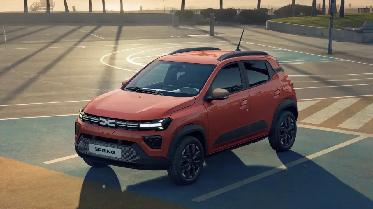 Pomarańczowy Dacia Spring na boisku. Sprawdź atrakcyjną dacia spring cena i odkryj jego możliwości.