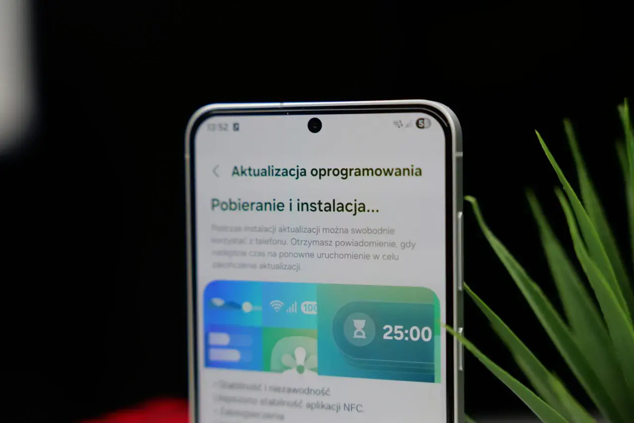 Telefon z interfejsem One UI 8.5 pokazuje ekran pobierania aktualizacji oprogramowania. Widoczny jest zegar 25:00.