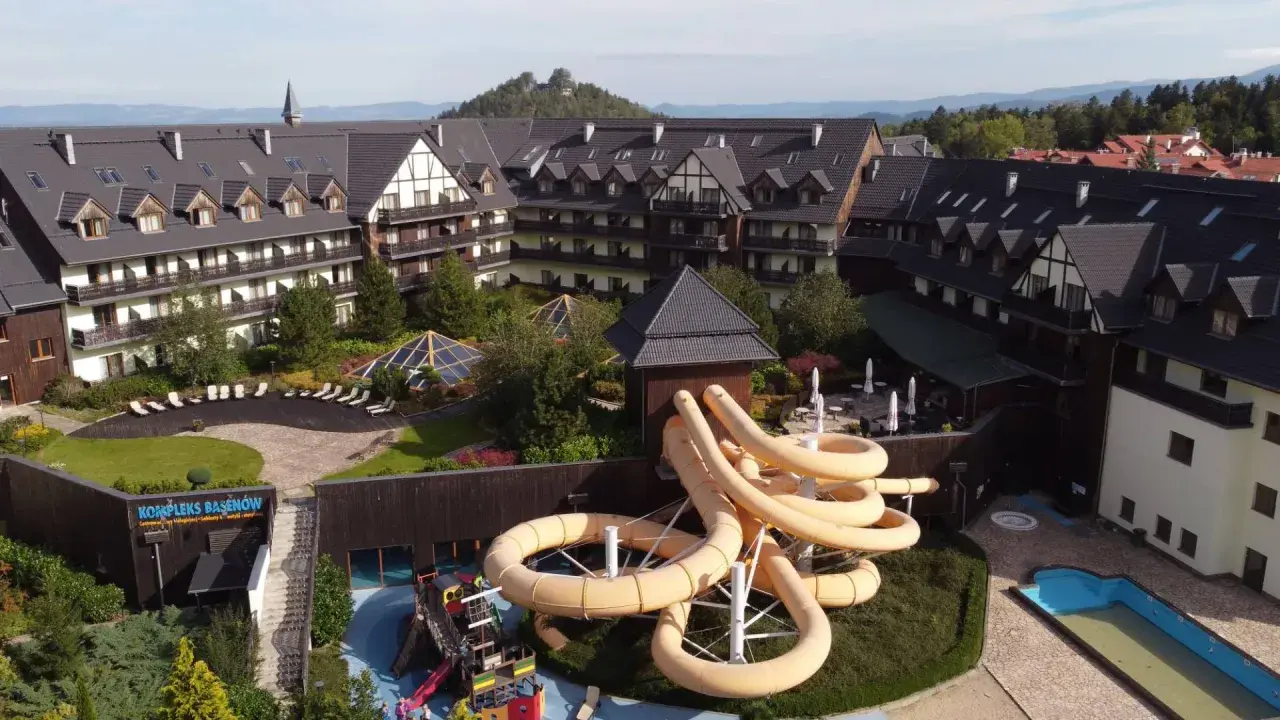 Karpacz hotel z aquaparkiem oferuje zjeżdżalnie i baseny. Widać też góry w tle.