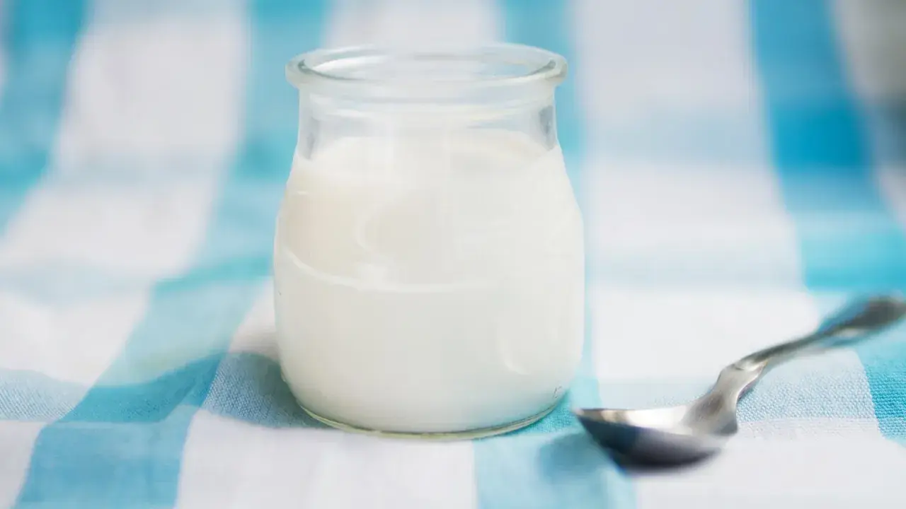 Słoiczek z domowym jogurtem, pełnym naturalnych probiotyków, czeka na łyżeczkę.