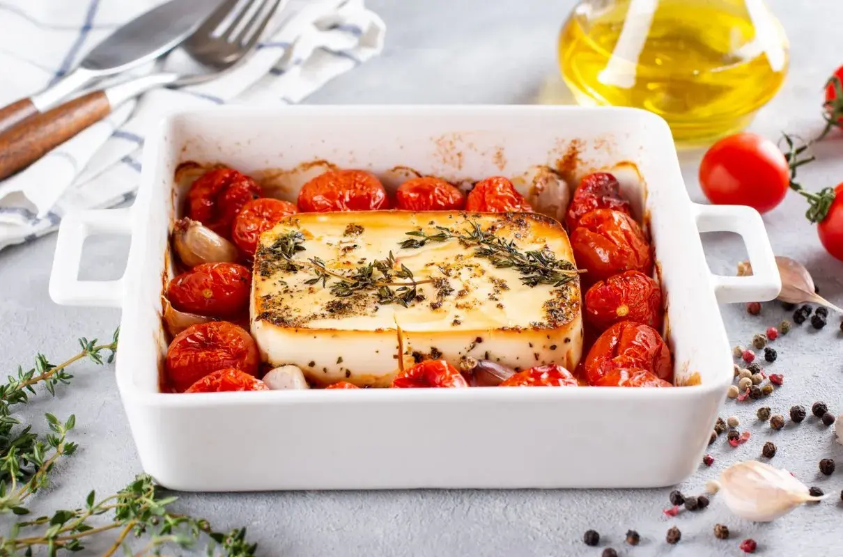 Pieczeni ser feta z pomidorkami koktajlowymi i czosnkiem, idealne dania na imprezę na ciepło.
