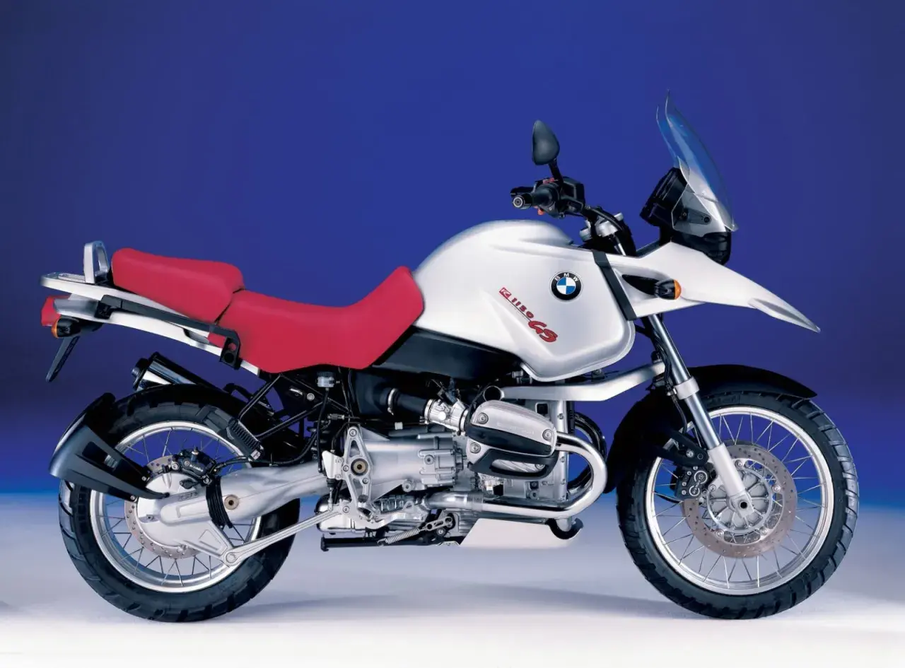 Srebrny motocykl BMW R 1150 GS z czerwoną kanapą, gotowy na przygodę.