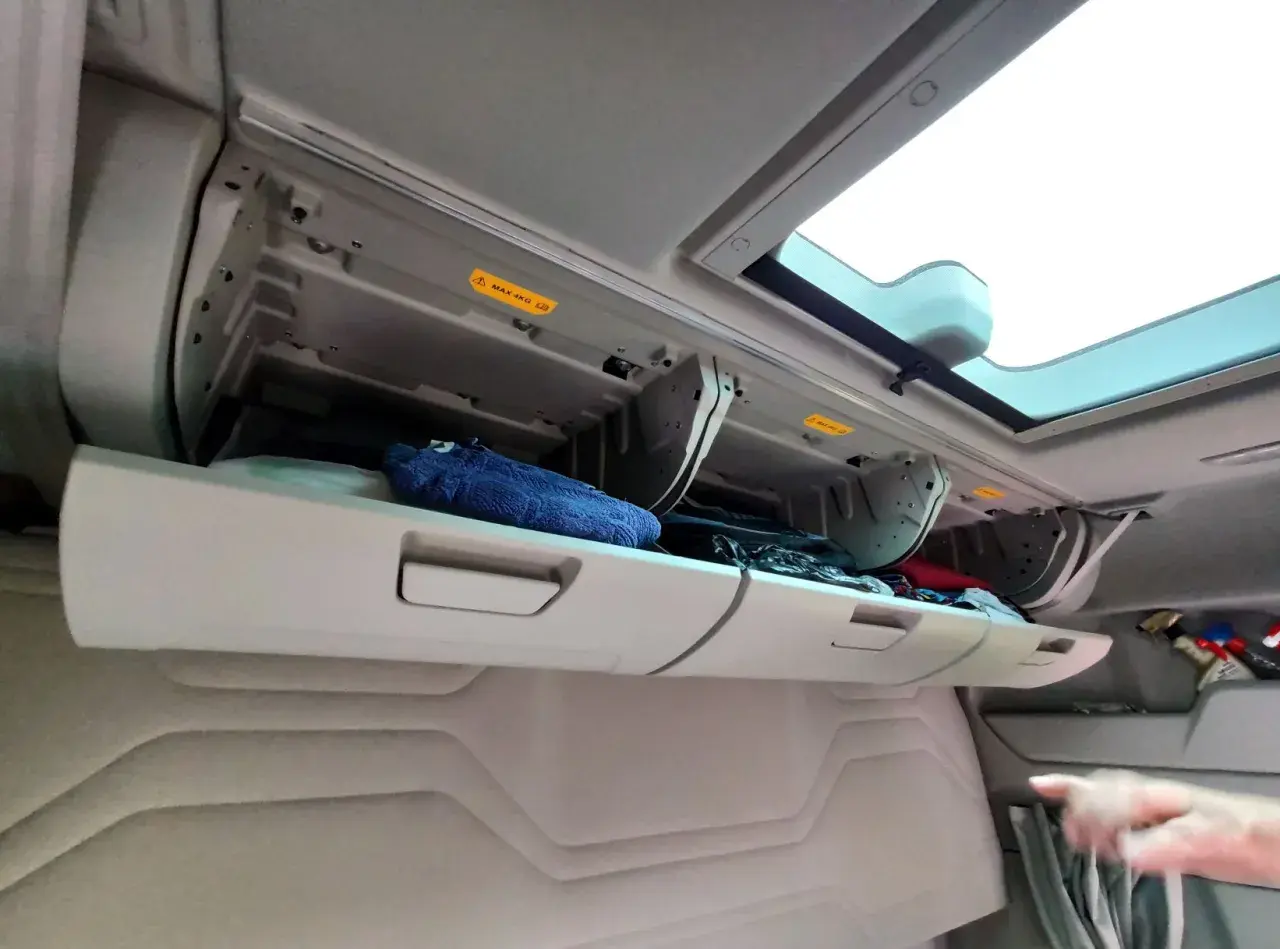 Schowek w kabinie Ford F-Max z niebieskim ręcznikiem i innymi przedmiotami.