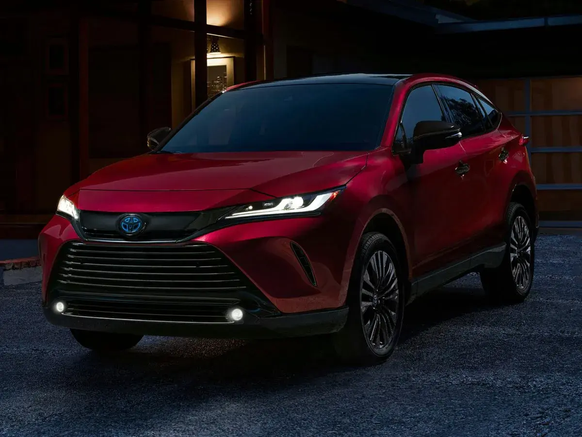 Elegancka, czerwona Toyota Venza z nowoczesnymi światłami LED stoi przed domem o zmierzchu.