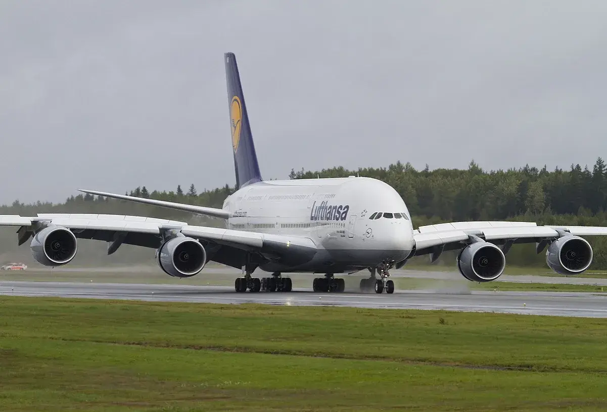 Lufthansa A380, największy samolot pasażerski, kołuje po mokrym pasie startowym.