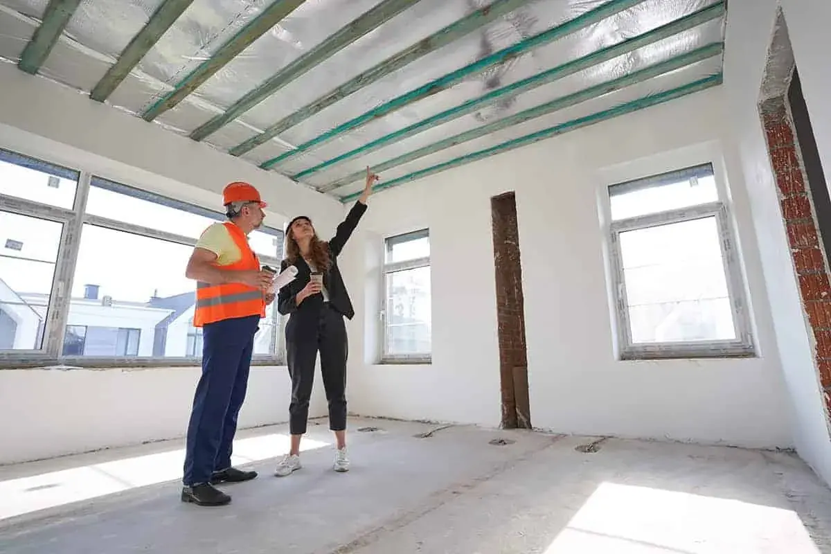 Inżynier i architektka omawiają projekt podwieszanego sufitu w nowym budynku.