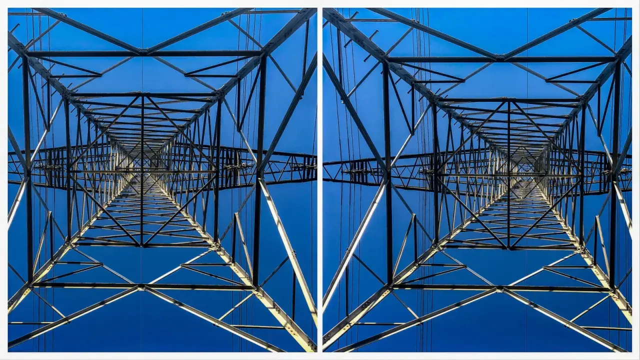 Widok z dołu na kratownicę słupa energetycznego, tworzącą geometryczny wzór na tle błękitnego nieba. To fotografia stereoskopowa.