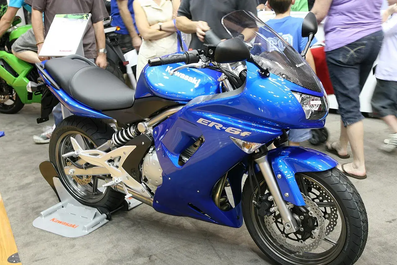 Błękitny motocykl Kawasaki ER-6f, z widocznymi danymi technicznymi na owiewce, prezentowany na wystawie.