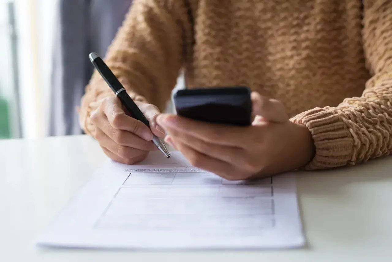 Kobieta z telefonem w dłoni wypełnia formularz, dokonując zgłoszenia darowizny online.
