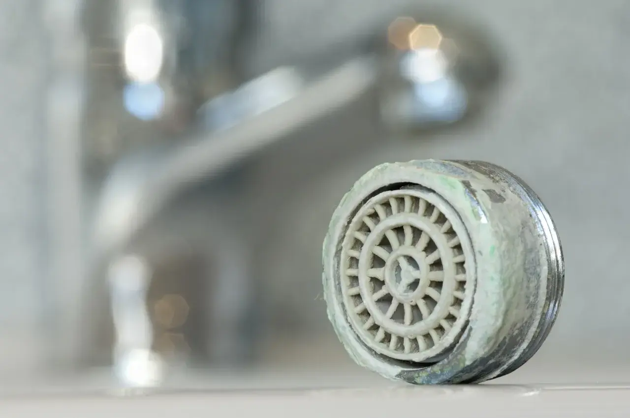 Zwapniony aerator kranu, który pokazuje, jak wyjąć sitko z kranu.