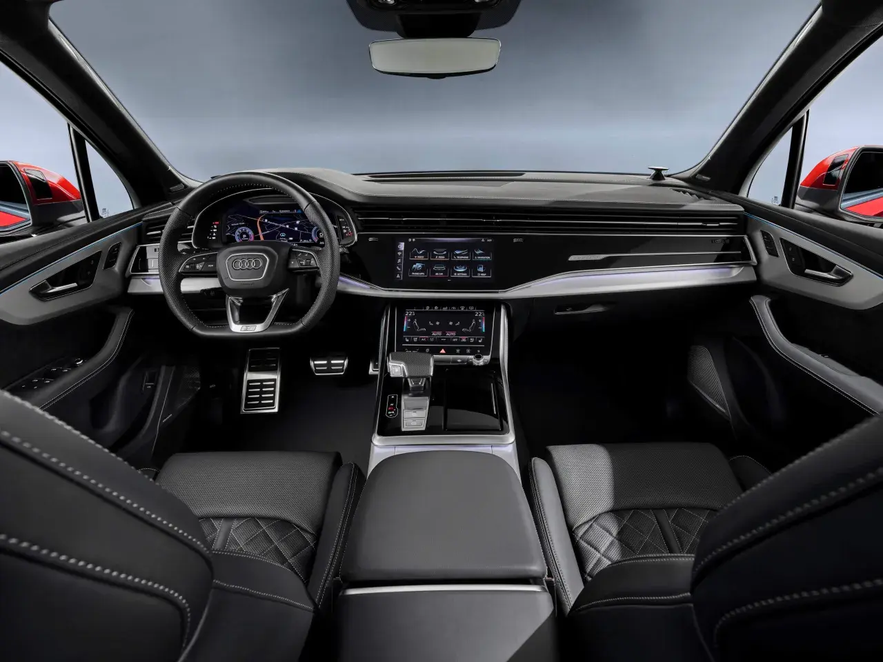 Wnętrze Audi Q7 z ekranami, kierownicą i skórzanymi fotelami.