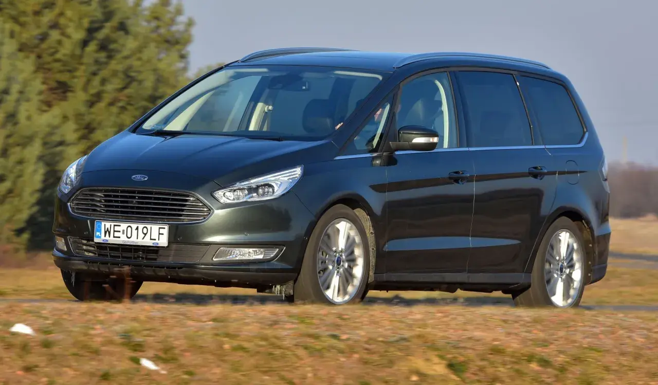 Ciemnozielony Ford Galaxy MK3 w ruchu, z polską tablicą rejestracyjną WE 019LF, przemierza wiejskie drogi.