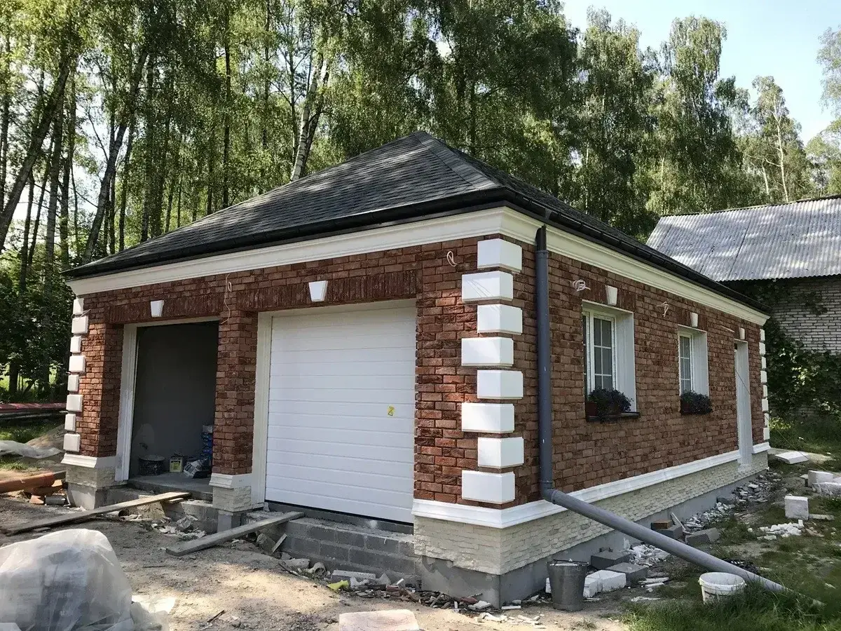 Nowy garaż z cegły z białym gzymsem i ozdobnymi elementami.